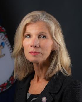 Secretary Lyn McDermid with the Commonwealth seal in the background