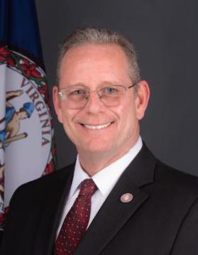 Headshot of Ken Pfeil with the Commonwealth seal in the background