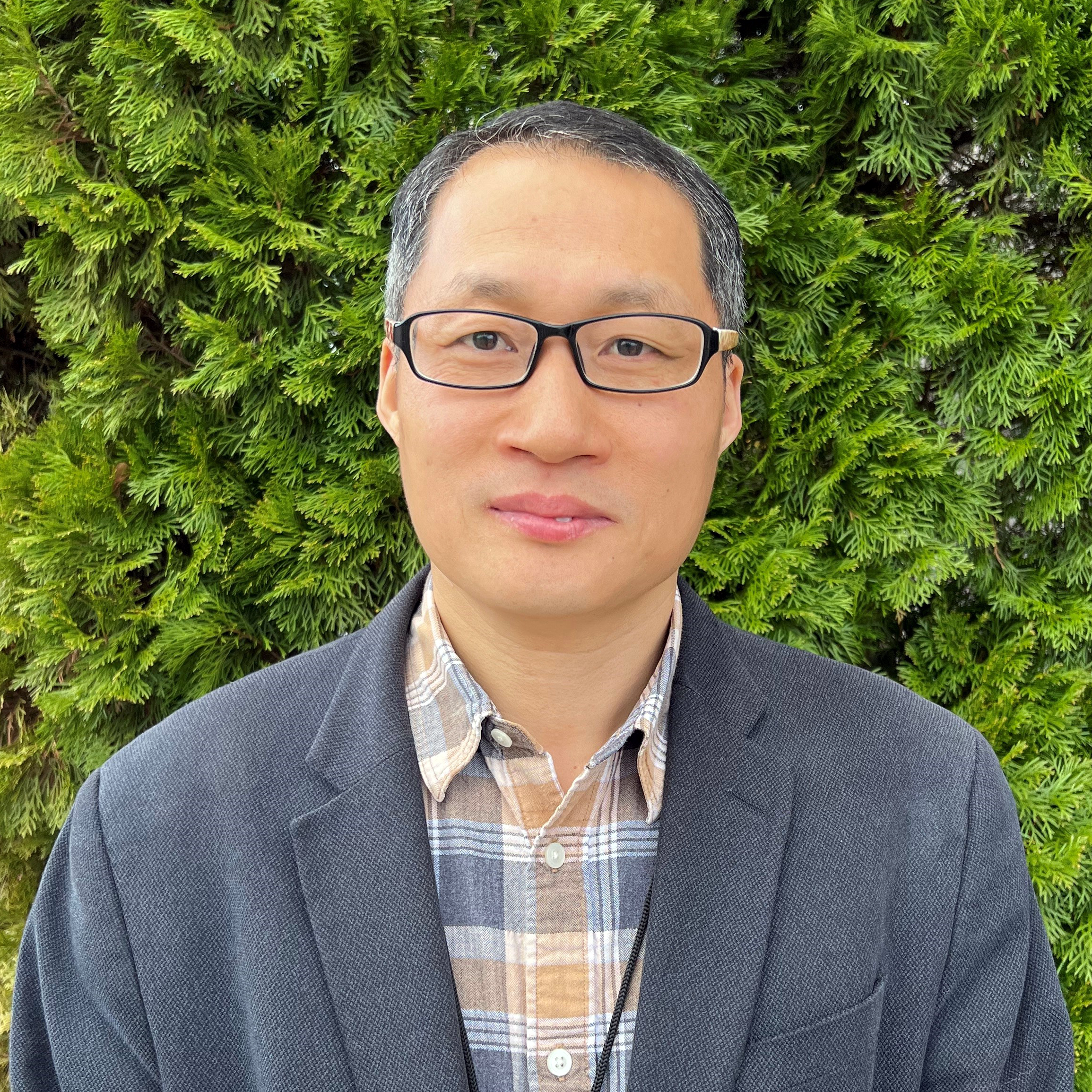Richard Liu, Power BI Developer, wears a blazer in his headshot in front of a bush