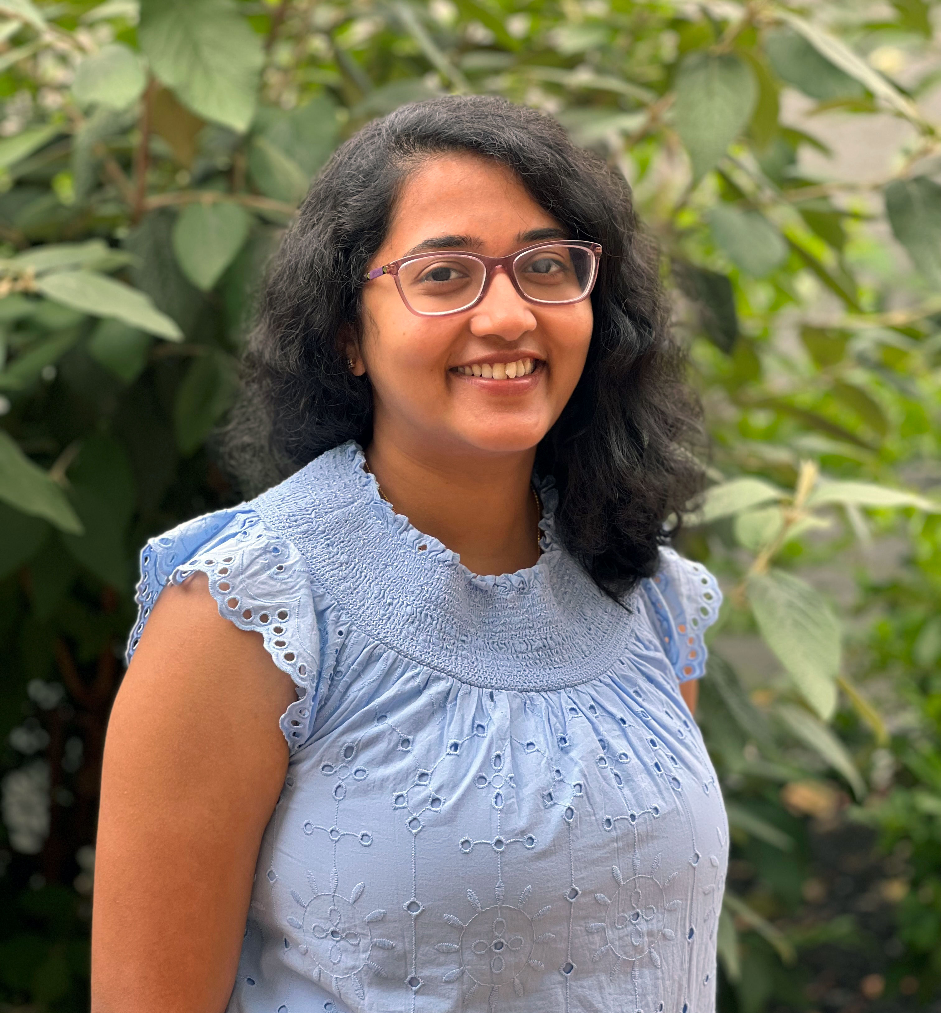Mounika Bobba, Data Analytics Specialist, wears a blouse in her headshot and stands in front of a tree